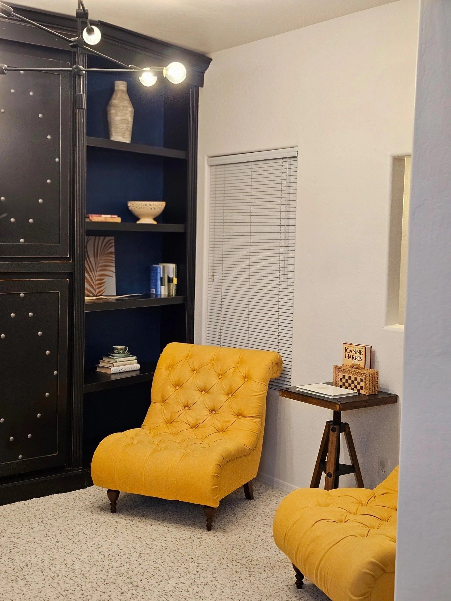 Den with a dark bookcase and yellow tufted chairs, cleaned