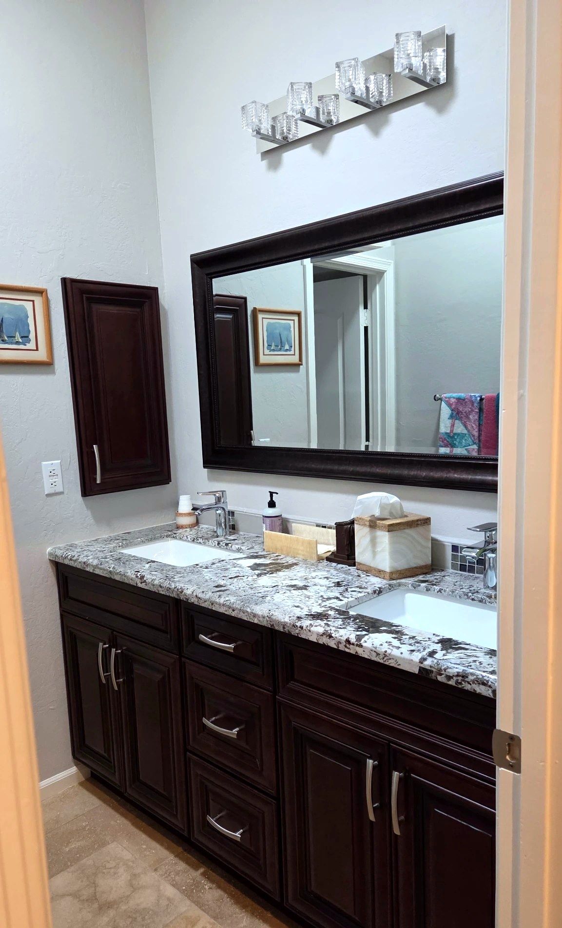 Double vanity with granite counters and dark wood cabinets, cleaned