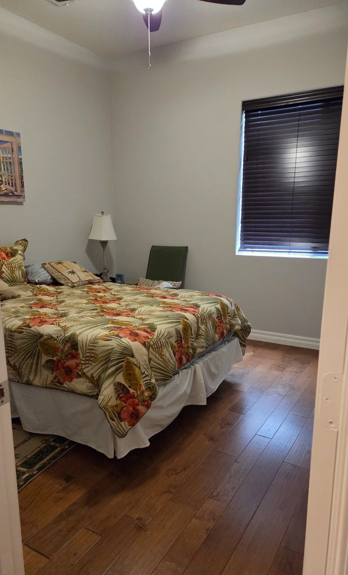 Guest bedroom with a made bed and clean hardwood floors