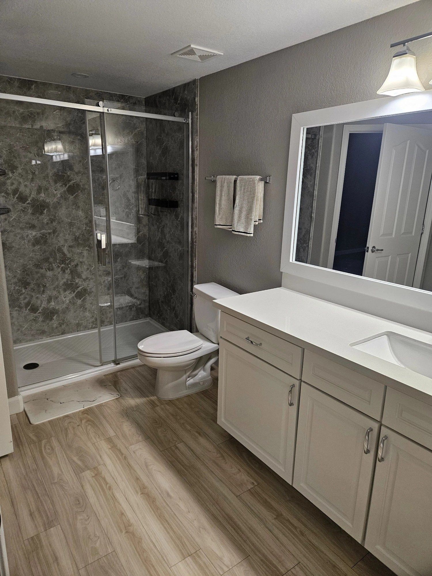 Empty bathroom with a glass shower and white vanity after a move-out clean